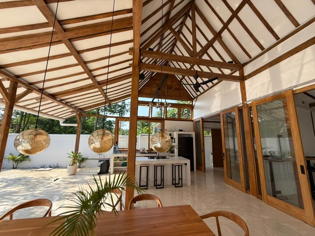 Open living room in Bali villa with modern design and natural light kitchen view